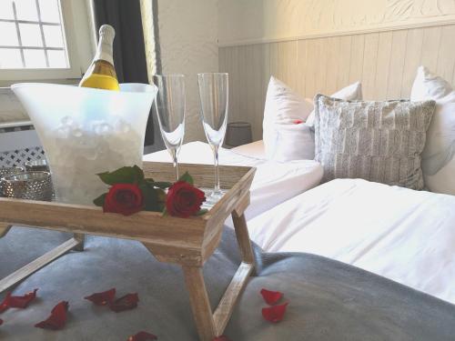 a bedroom with two wine glasses and roses on a table at Pension Zur Alten Post in Havelberg