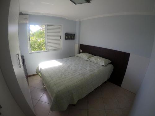 Habitación pequeña con cama y ventana en JURERE INTERNACIONAL COSTA BLANCA, en Florianópolis