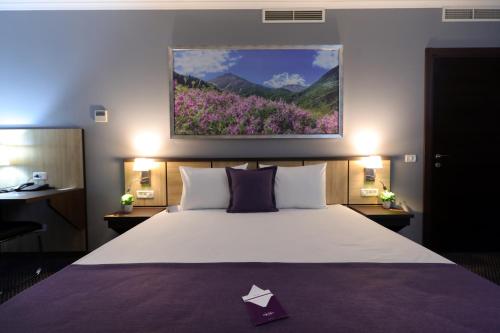 1 dormitorio con 1 cama grande con una pintura floral en la pared en Mercure Tetovo, en Tetovo