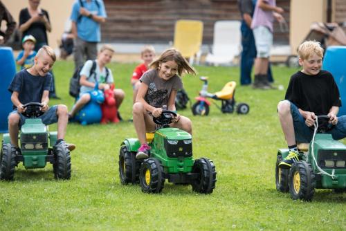 a group of children playing on toy tractors in the grass at Reitstall und Saloon San Jon in Scuol