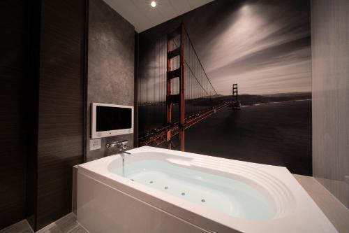 a bathroom with a bath tub with a painting of the golden gate bridge at ホテル ポルト 男塾ホテルグループ in Himeji