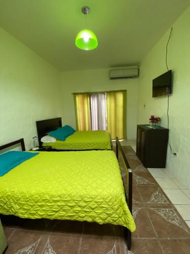 a bedroom with two beds with green sheets and a television at Zurisadai in Puerto Ayora