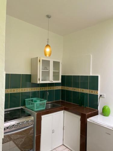 a kitchen with white cabinets and green tiled walls at Zurisadai in Puerto Ayora