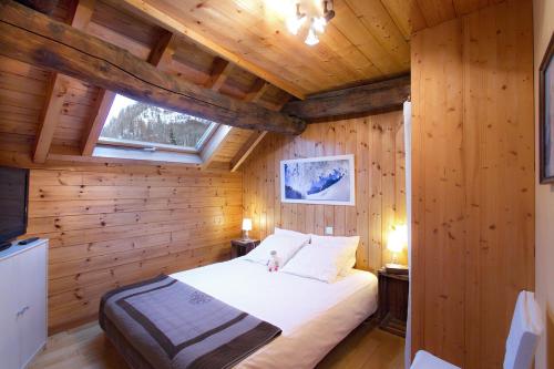een slaapkamer met een bed in een houten hut bij Chalet Les Copains in Les Deux Alpes