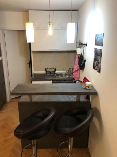 a kitchen with two black stools in front of a counter at Apartman Ana in Dušanovac (historical)