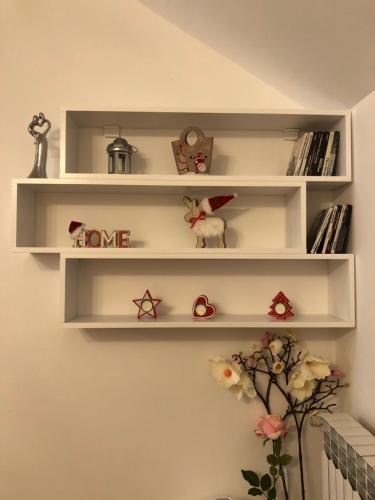 a white shelf on a wall with figurines and books at Apartman Ana in Dušanovac (historical)