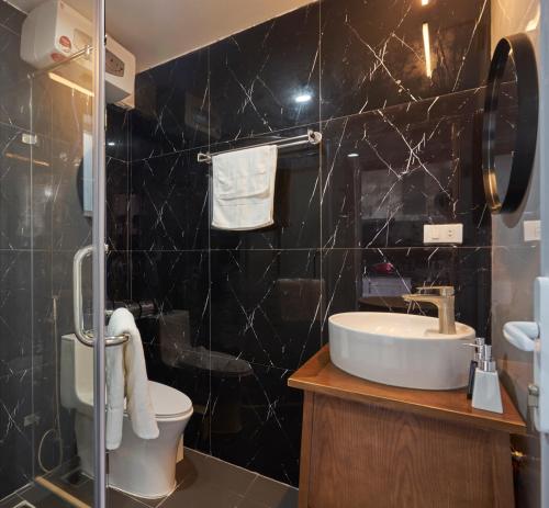 a black tiled bathroom with a sink and a toilet at Little Colmar - Homestay & Pottery Studio in Ha Long