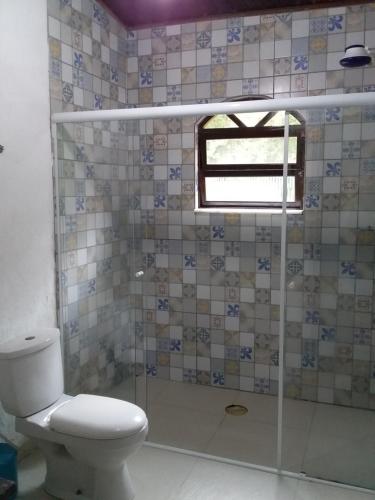 ein Bad mit einem WC und einer Glasdusche in der Unterkunft Suites próximo ao rio Jaguareguava em Bertioga in Bertioga