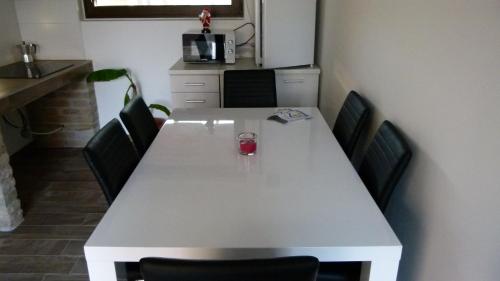 a white table with chairs and a glass of wine on it at Duna Dráva Vendégház in Érsekcsanád
