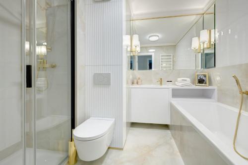 a white bathroom with a toilet and a shower at Dom & House - Apartments Winter Residence in Gdańsk