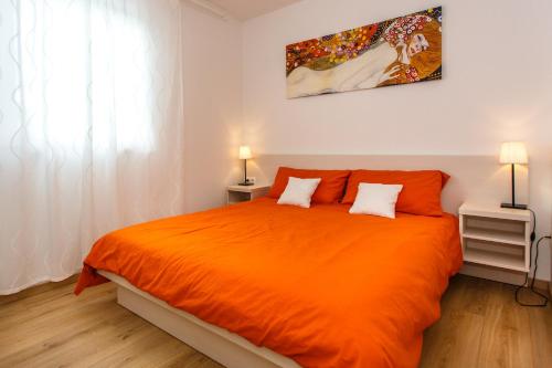 un letto arancione in una camera bianca con due lampade di Palmer Residence Krk a Dobrinj