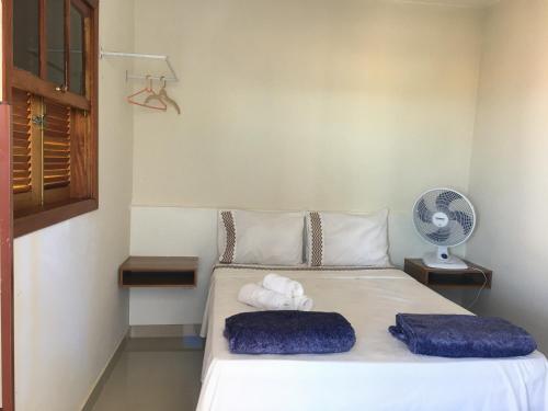 a bedroom with a bed with towels and a fan at Suites Cerrado in Alto Paraíso de Goiás