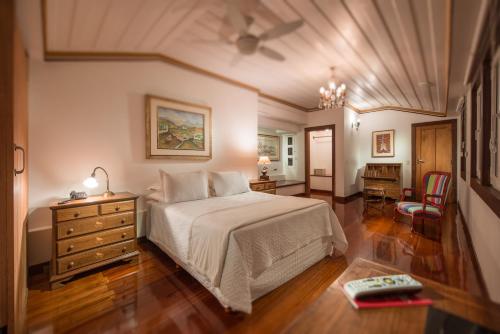 a bedroom with a large bed and a dresser and a ceiling at Pousada do Mondego in Ouro Preto