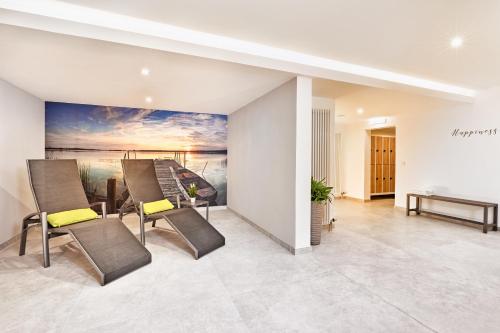 a living room with chairs and a painting on the wall at H+ Hotel Stuttgart Herrenberg in Herrenberg