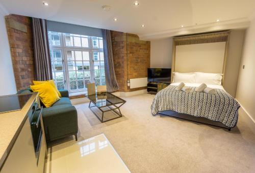 Riverside Studio Apartments Close To City Centre في يورك: غرفة نوم كبيرة مع سرير وأريكة