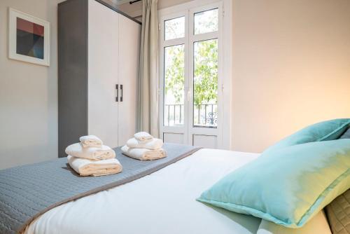 a bedroom with towels on a bed with a window at The Family Host - Lost Garden Ciutadella Park in Barcelona