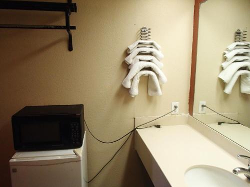 a bathroom with a sink and a microwave and towels at Sunrise Inn Lake Charles in Lake Charles