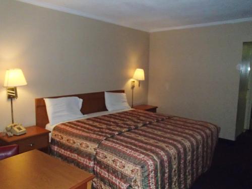 a hotel room with a bed and a table and two lamps at Sunrise Inn Lake Charles in Lake Charles