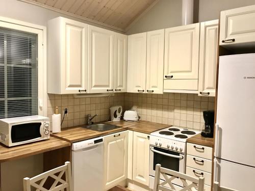 a kitchen with white cabinets and a sink and a microwave at Villa Sidori in Jämsä