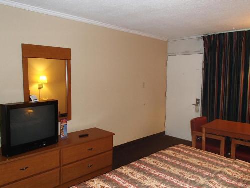 a hotel room with a bed and a flat screen tv at Sunrise Inn Lake Charles in Lake Charles