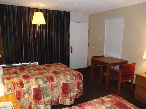 a hotel room with a bed and a desk and a table at Sunrise Inn Lake Charles in Lake Charles