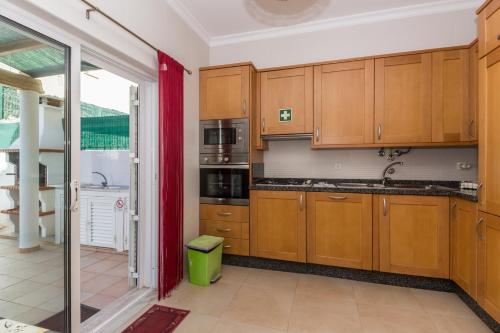 a kitchen with wooden cabinets and a red curtain at Villa Amoreira by ALGARVEMANTA in Manta Rota