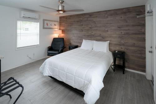 a bedroom with a large white bed and a chair at Sun Outdoors Key Largo in Key Largo