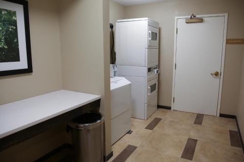 a white kitchen with a refrigerator and a trash can at Candlewood Suites - Portland - Scarborough, an IHG Hotel in Scarborough