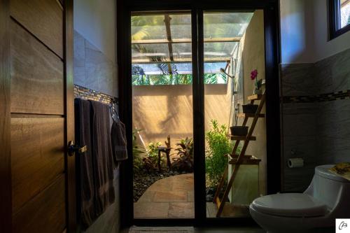 a bathroom with a toilet sitting next to a door at Hotel Casa Buenavista - Adults only in Sámara