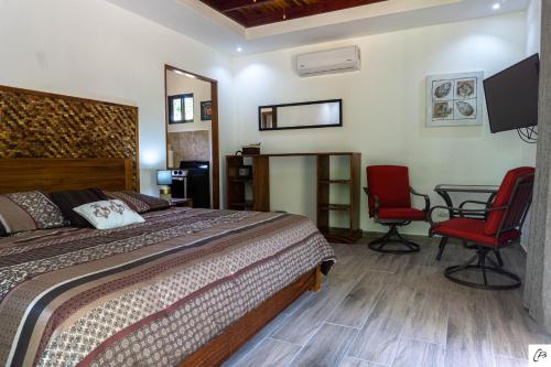 a bedroom with a bed and two chairs and a table at Hotel Casa Buenavista - Adults only in Sámara
