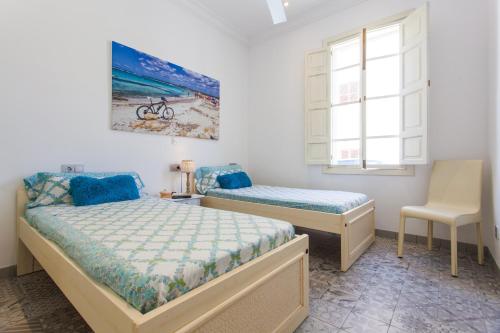 a bedroom with two beds and a chair at Beach House Sa Torre in Colònia de Sant Jordi