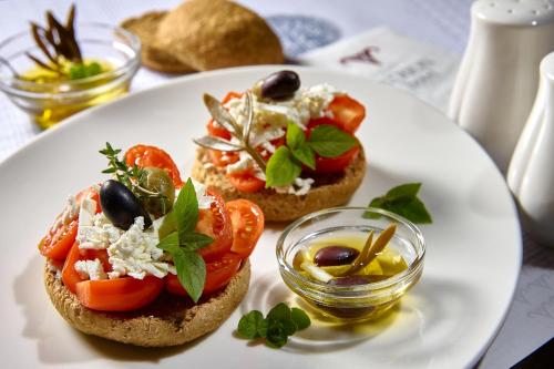 a white plate with three sandwiches with tomatoes and cheese at Atrion Hotel in Heraklio