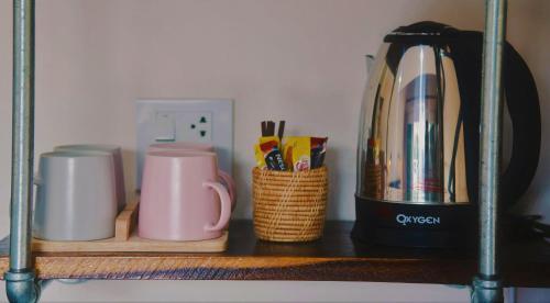 a shelf with two cups and a coffee maker on it at Boutique Family Room Phitsanulok in Phitsanulok