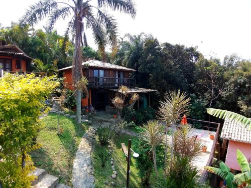 a house with a palm tree in the yard at Pousada Uhuru in Praia do Rosa