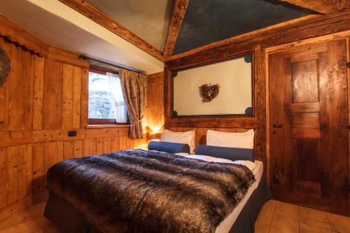 a bedroom with a large bed in a room with wooden walls at Au Coeur Des Neiges Resort SPA & FREE E-BIKE in Courmayeur