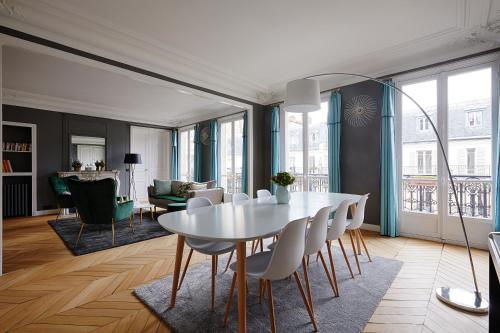 une salle à manger et un salon avec une table et des chaises blanches dans l'établissement Veeve - Emerald Exuberance, à Paris