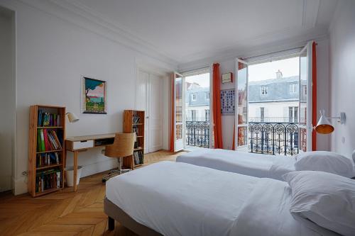 une chambre avec deux lits et un bureau et une fenêtre dans l'établissement Veeve - Emerald Exuberance, à Paris
