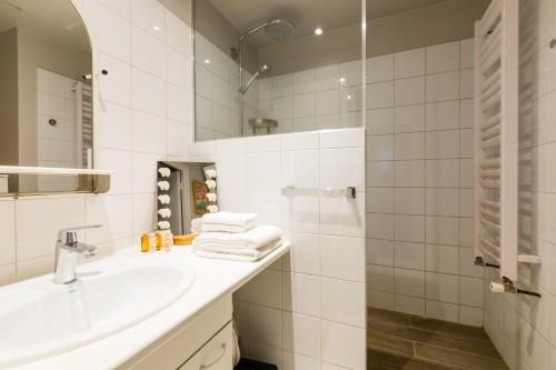 une salle de bain blanche avec un lavabo et un miroir dans l'établissement Veeve - Quai aux Fleurs Apartment, à Paris