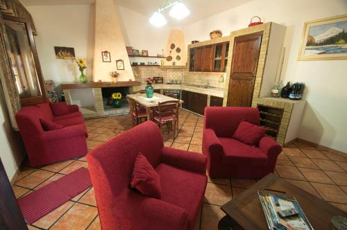 een woonkamer met 2 rode stoelen en een tafel bij Casa Sa Carrubedda in SantʼAnna Arresi
