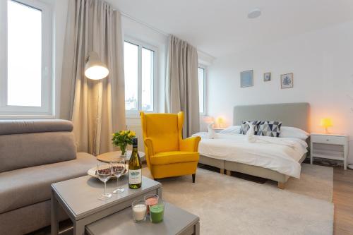 a living room with a bed and a yellow chair at Harfa Apartments in Prague