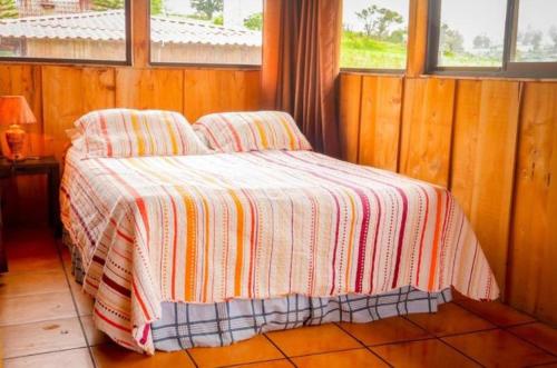 a bedroom with a bed with a striped blanket at Hotel Chalets Los Volcanes in Alajuela City