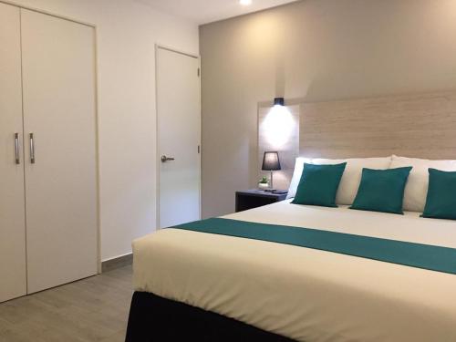 1 dormitorio con 1 cama grande con almohadas azules en Suite Ejecutiva Ardres Plaza, en Quito