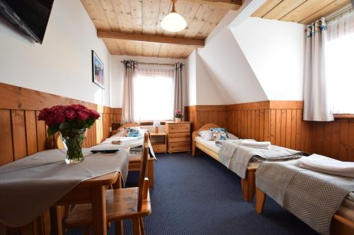 Willa Świdrówka 2 في بورونين: غرفة بسريرين وطاولة عليها ورد