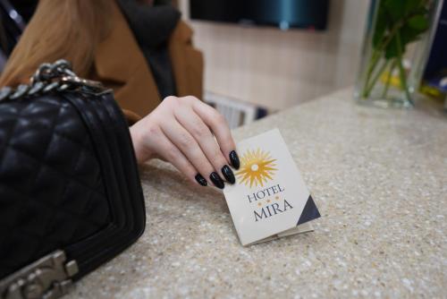 a person holding a card on a counter with a hand at Mira Hotel in Moscow