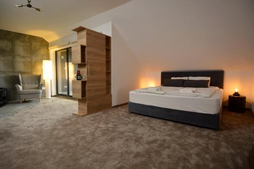a large bedroom with a large bed and a chair at Ludwig Hotel in Martonvásár