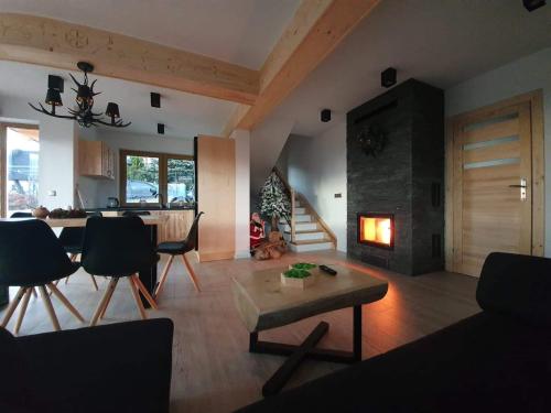 a living room with a fireplace and a table and chairs at Domek z widokiem na Tatry in Gliczarów