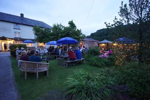 a group of people sitting under umbrellas in a garden at Furzeleigh Mill Inn in Buckfastleigh