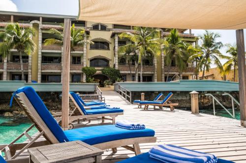 una terraza con tumbonas azules y una piscina en The Bellafonte - Luxury Oceanfront Hotel, en Kralendijk