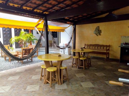 2 mesas y sillas en una habitación con hamaca en Arco Íris Pousada en Ilha Comprida
