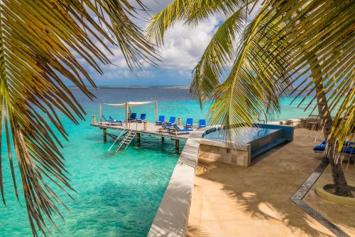 un muelle en el océano con sillas y una palmera en The Bellafonte - Luxury Oceanfront Hotel en Kralendijk